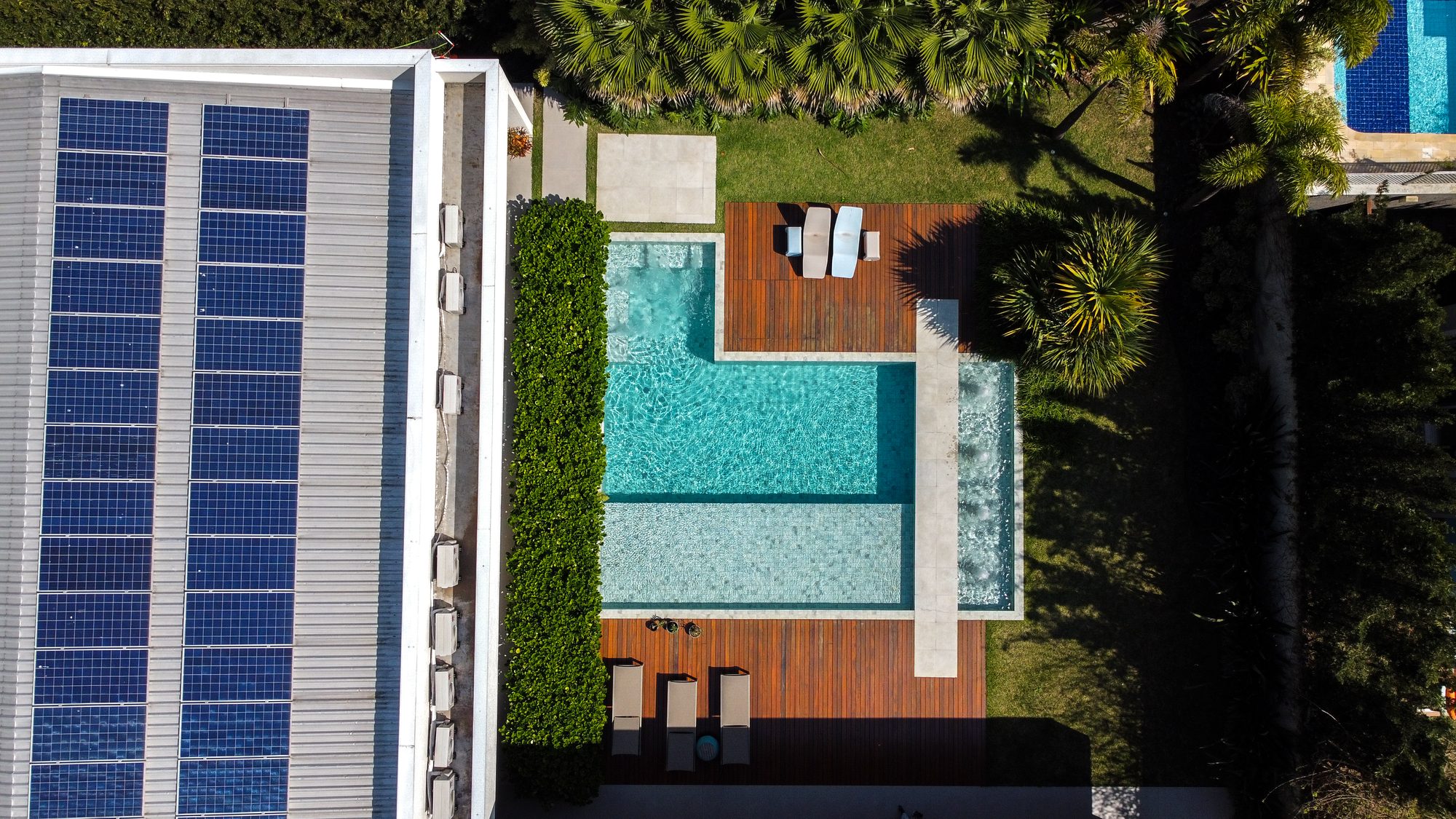 Vista aérea de piscina com deck de madeira e jardim
