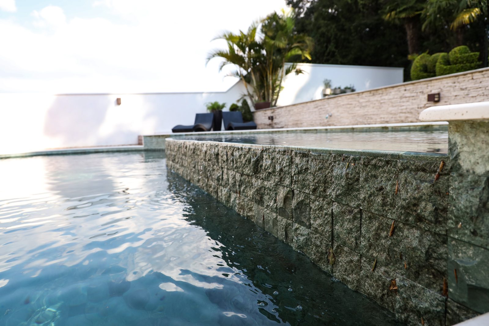 Piscina com borda infinita e parede em pedra natural