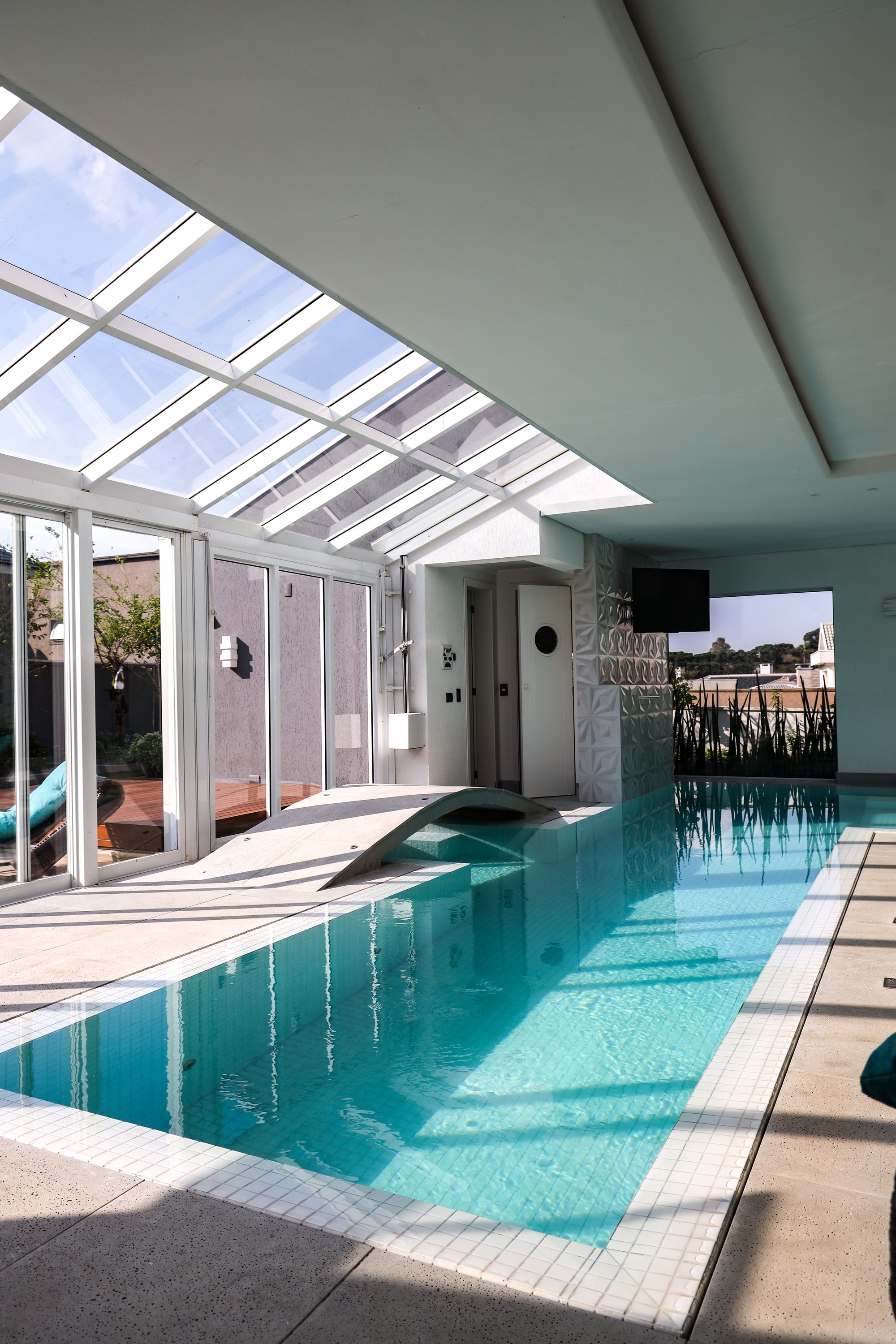 Piscina coberta com cobertura de vidro e espreguiçadeiras