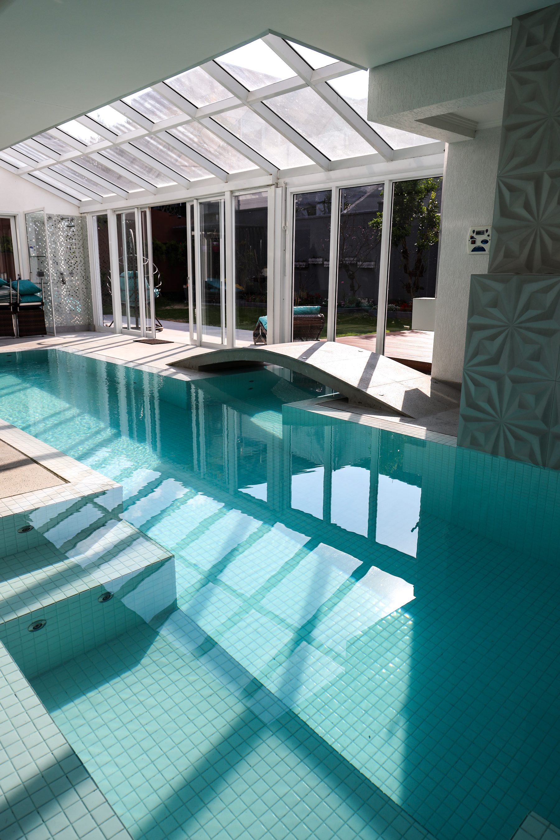 Piscina coberta com estrutura de vidro e luz natural