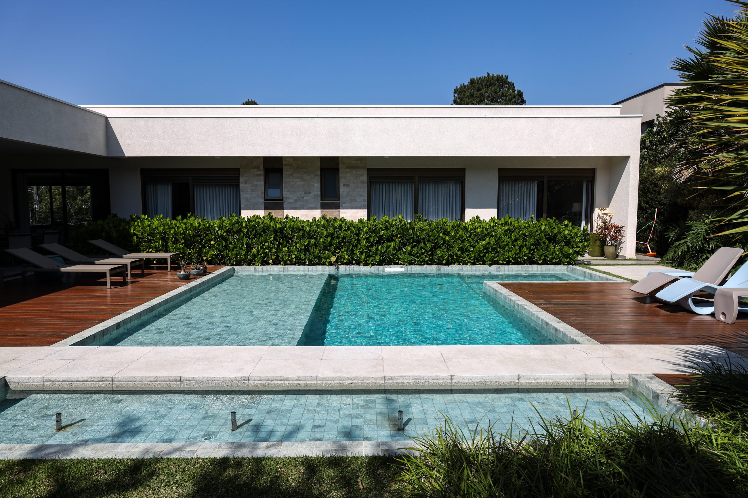 Piscina de alto padrão executada pela Naussat, integrada à arquitetura de uma residência contemporânea