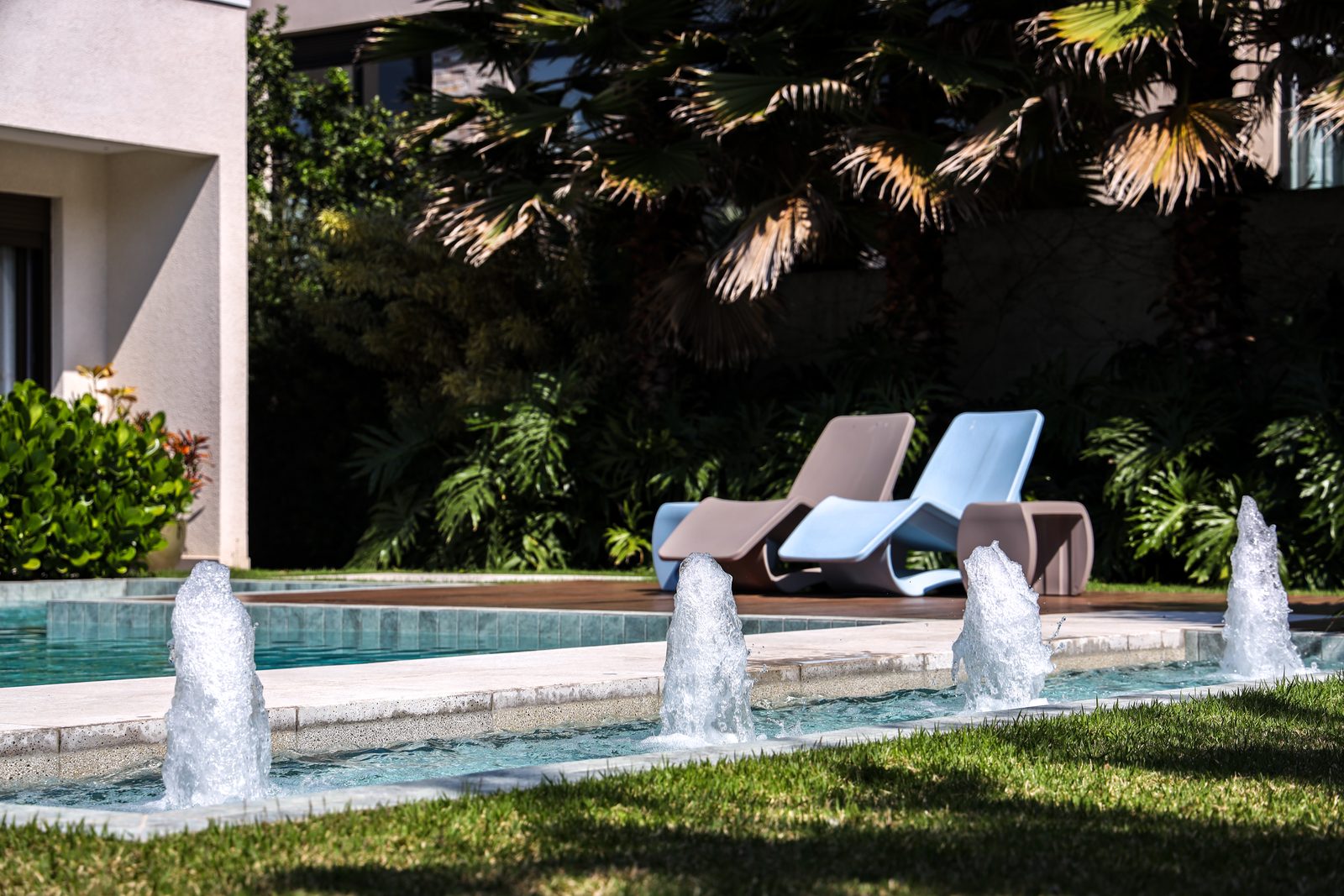 Espreguiçadeiras à beira da piscina com jatos de água