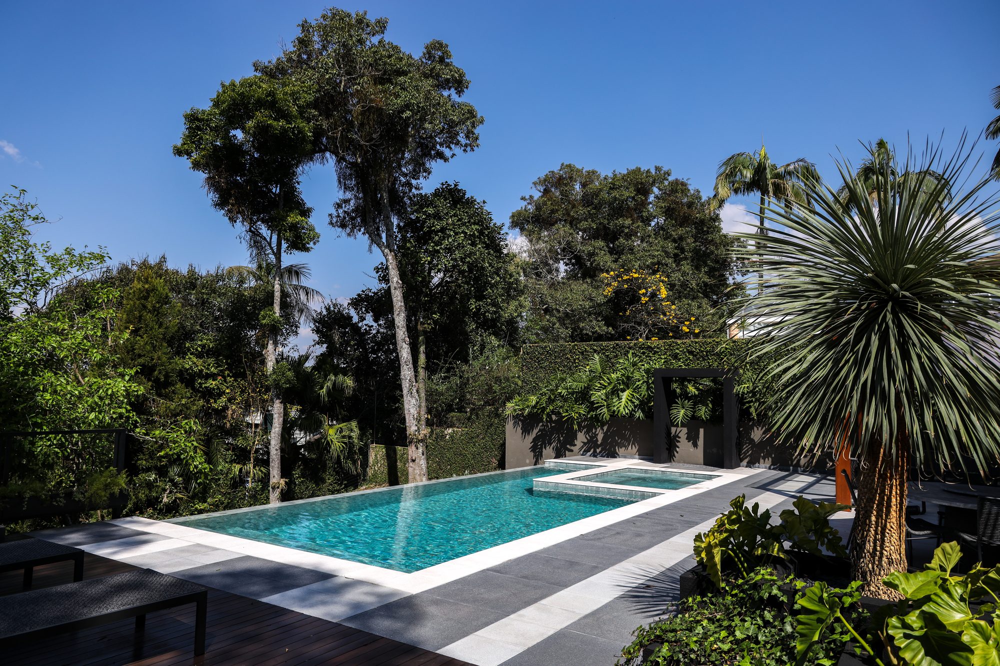 Piscina ampla estilo resort integrada ao jardim