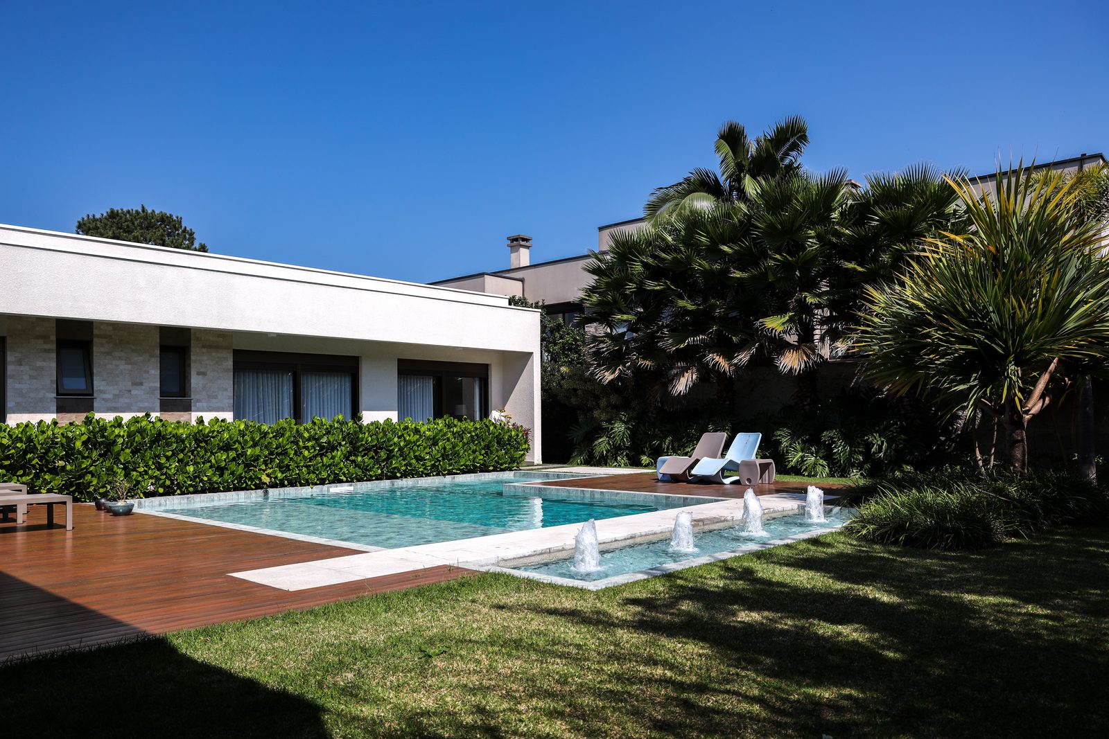 Piscina com jatos de água em frente a residência contemporânea