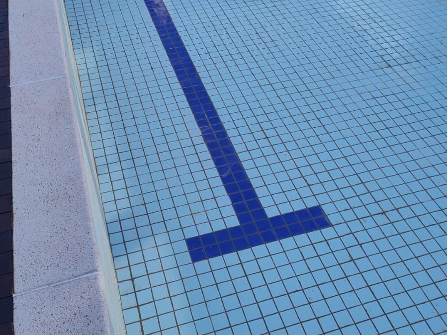 Piscina com revestimento cerâmico azul e raia marcada no fundo
