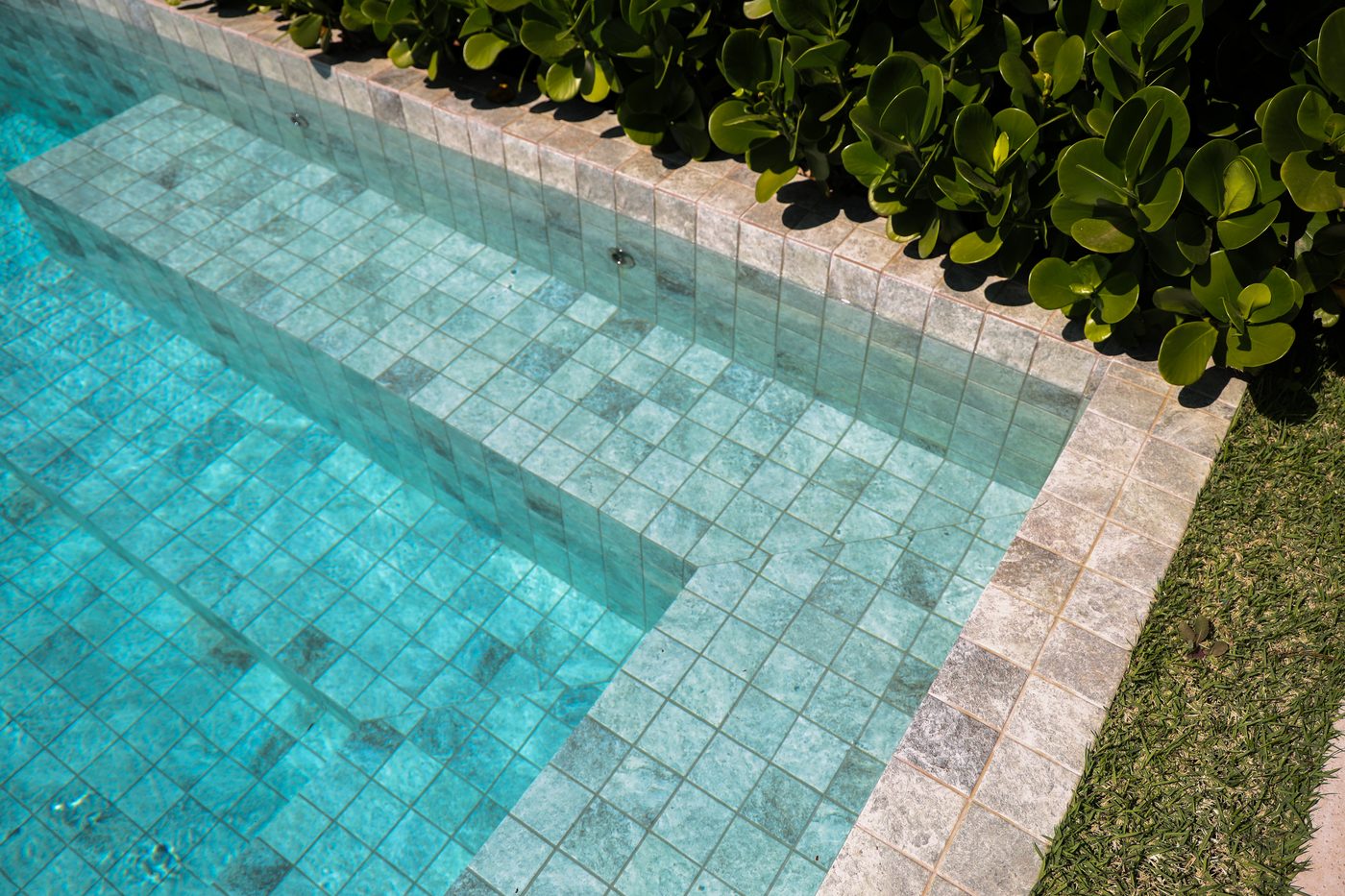 Detalhe de revestimento em pedra natural na borda de uma piscina Naussat